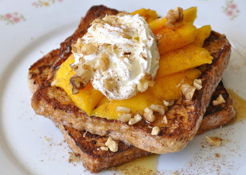 Wheat bread French toast topped with sliced fresh mangoes, honey, whipped cream and chopped walnuts