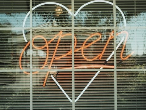 Neon 'Open' sign framed in a heart-shape in a window Photographic Print