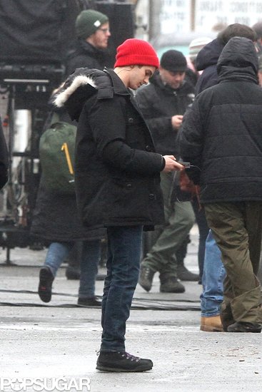 Andrew Garfield bundled up in a red beanie and black coat on the set.
Andrew Garfield bundled up in a red beanie and black coat on the set.