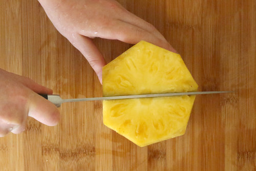 Next, cut the pineapple down the center.
Next, cut the pineapple down the center.