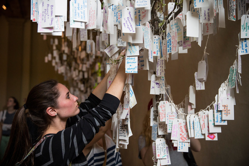 A woman hung her handwritten message on a tree of notes at the Boston Public Library's memorial exhibition. A woman hung her handwritten message on a tree of notes at the Boston Public Library's memorial exhibition.