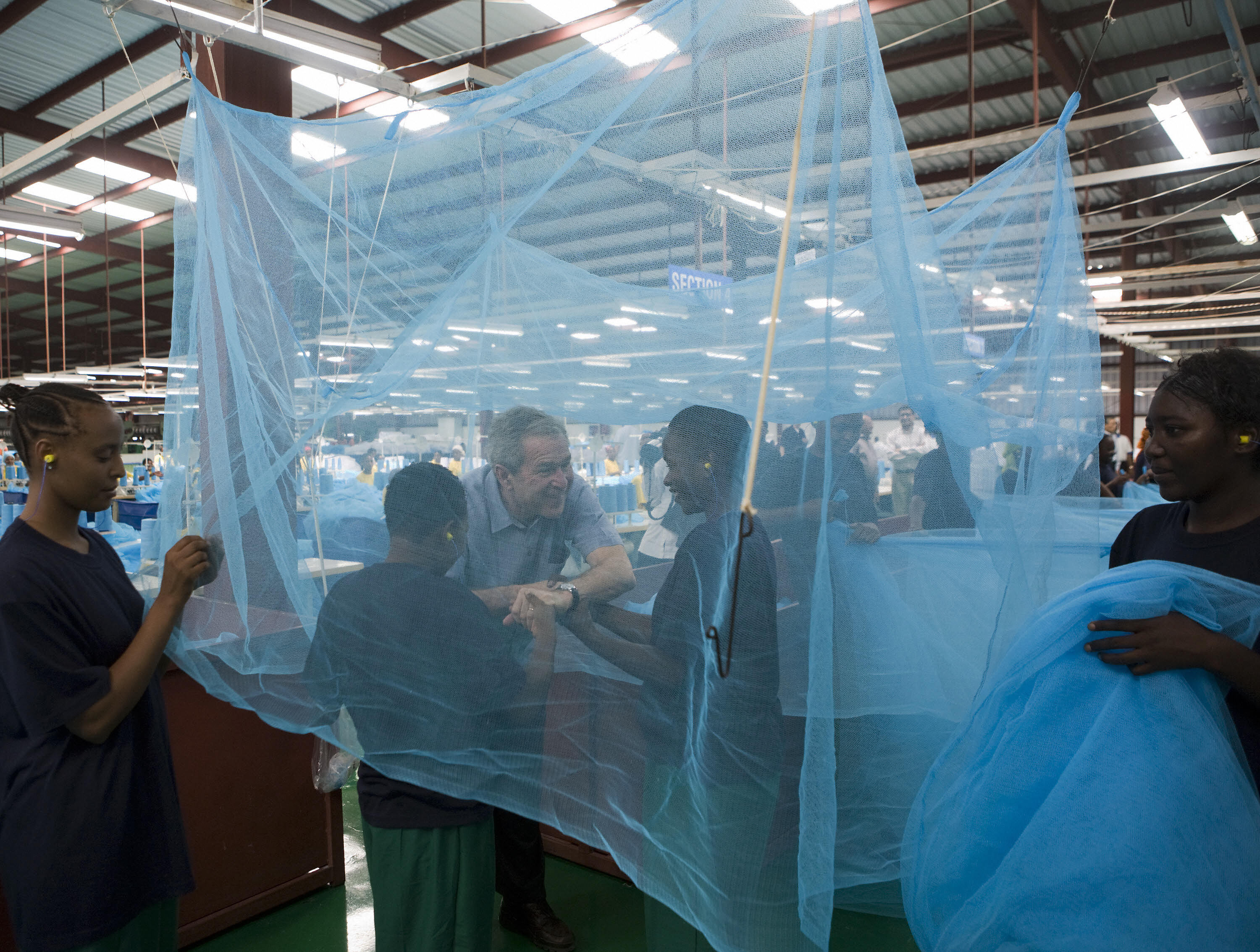 Bush greets workers under a mosquito bed net in Tanzania. Bush greets workers under a mosquito bed net in Tanzania.