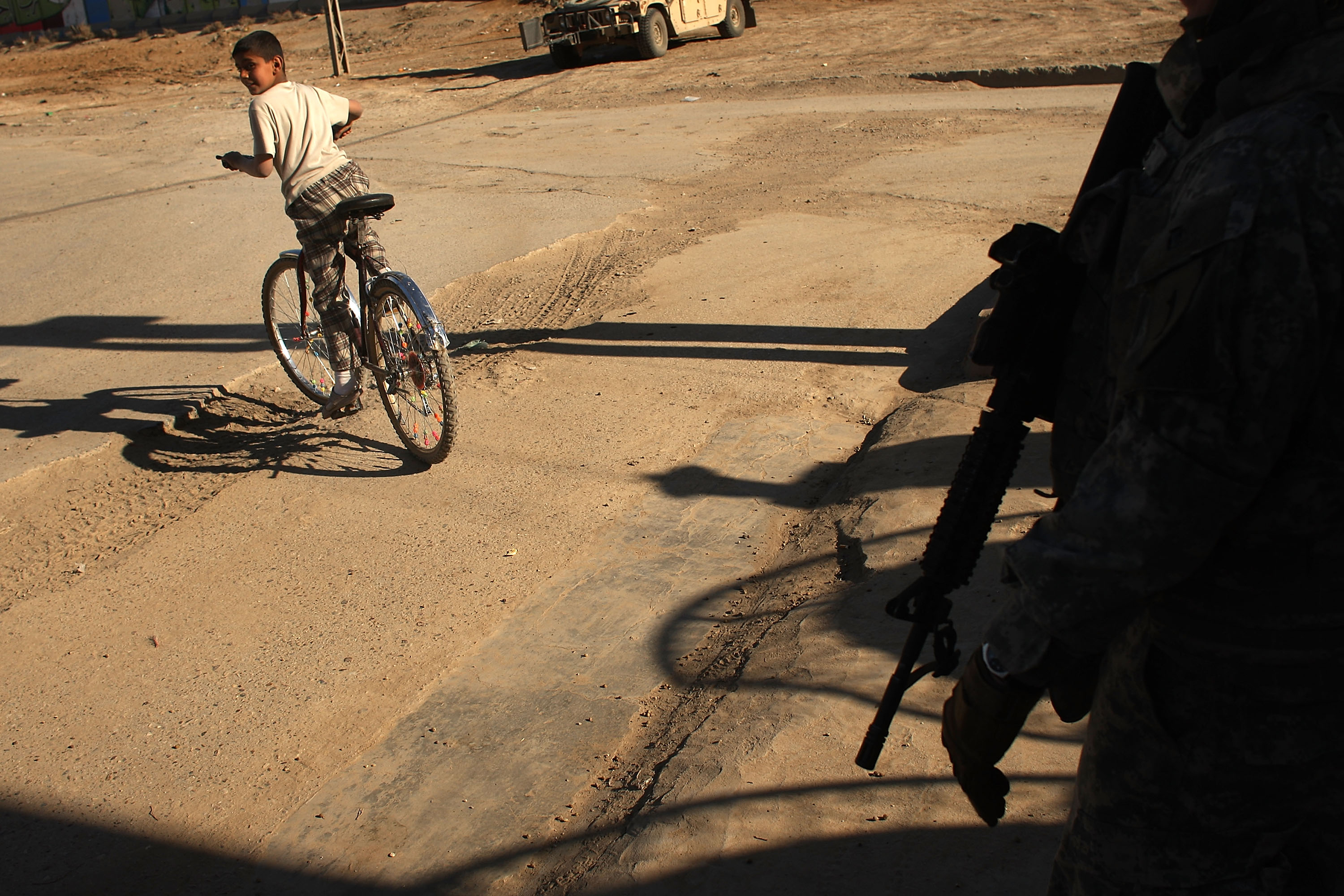 A boy rides his bicycle past US soldiers, March 6, 2008. A boy rides his bicycle past US soldiers, March 6, 2008.