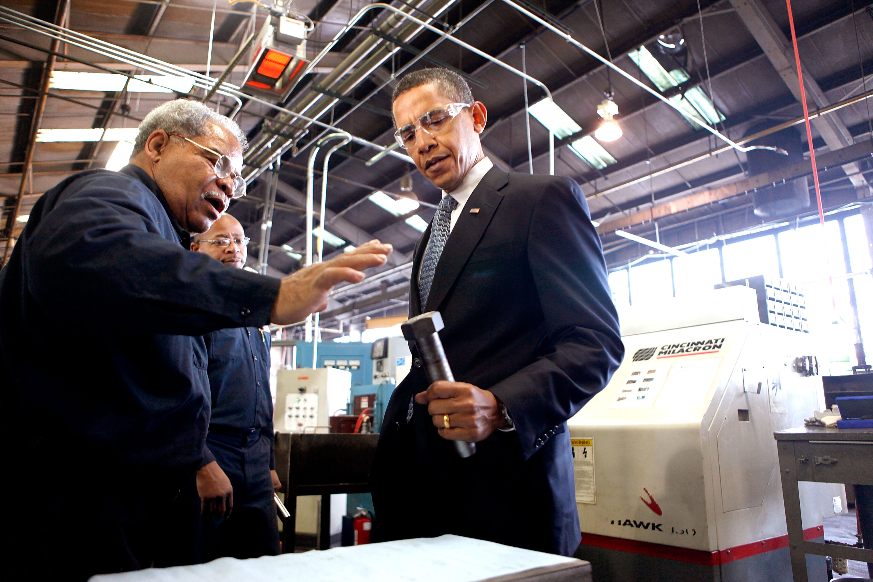 A worker shows Obama how he makes large bolts used for bridge construction. A worker shows Obama how he makes large bolts used for bridge construction.
