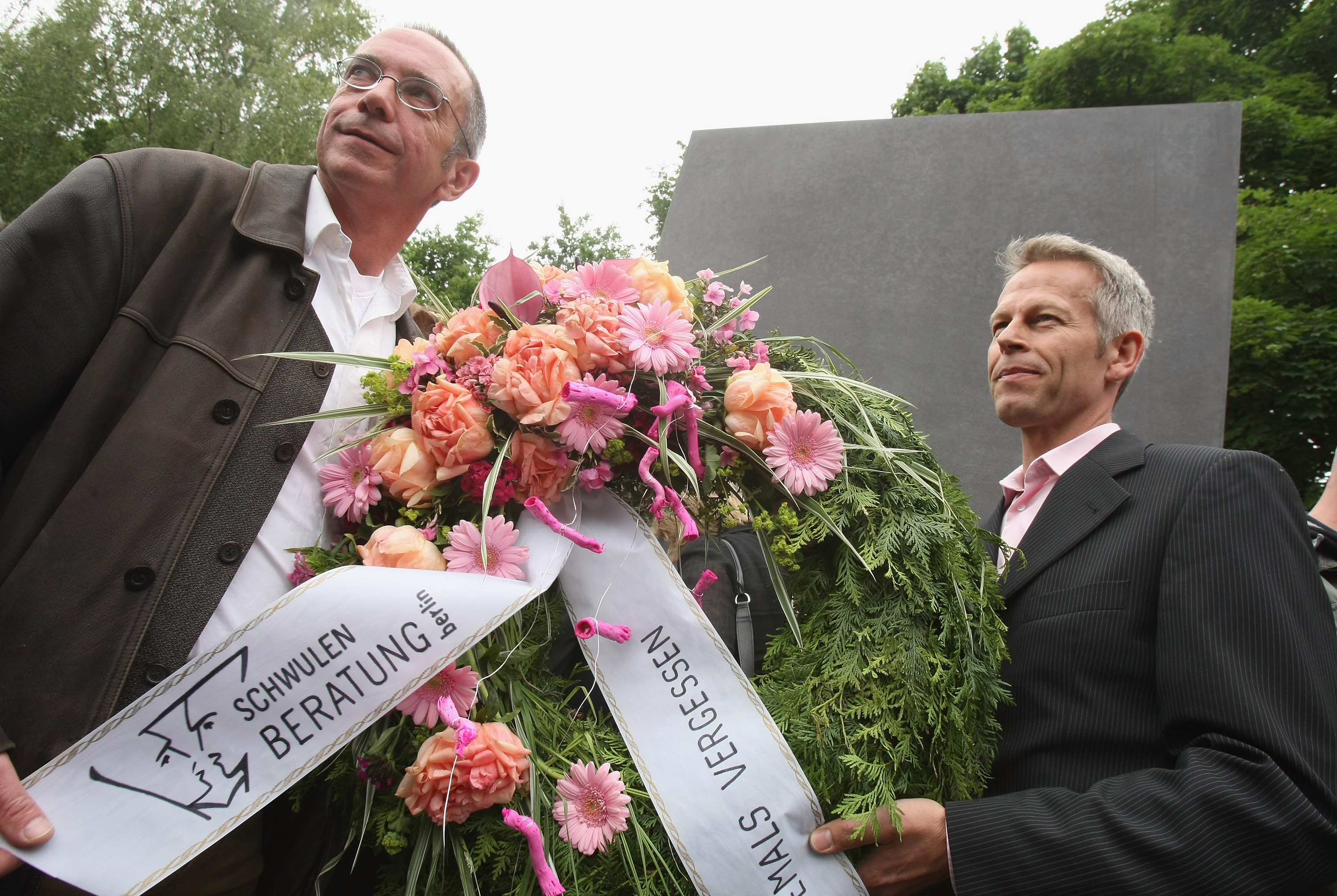 Two men from a gay counseling organization hold a wreath. Two men from a gay counseling organization hold a wreath.