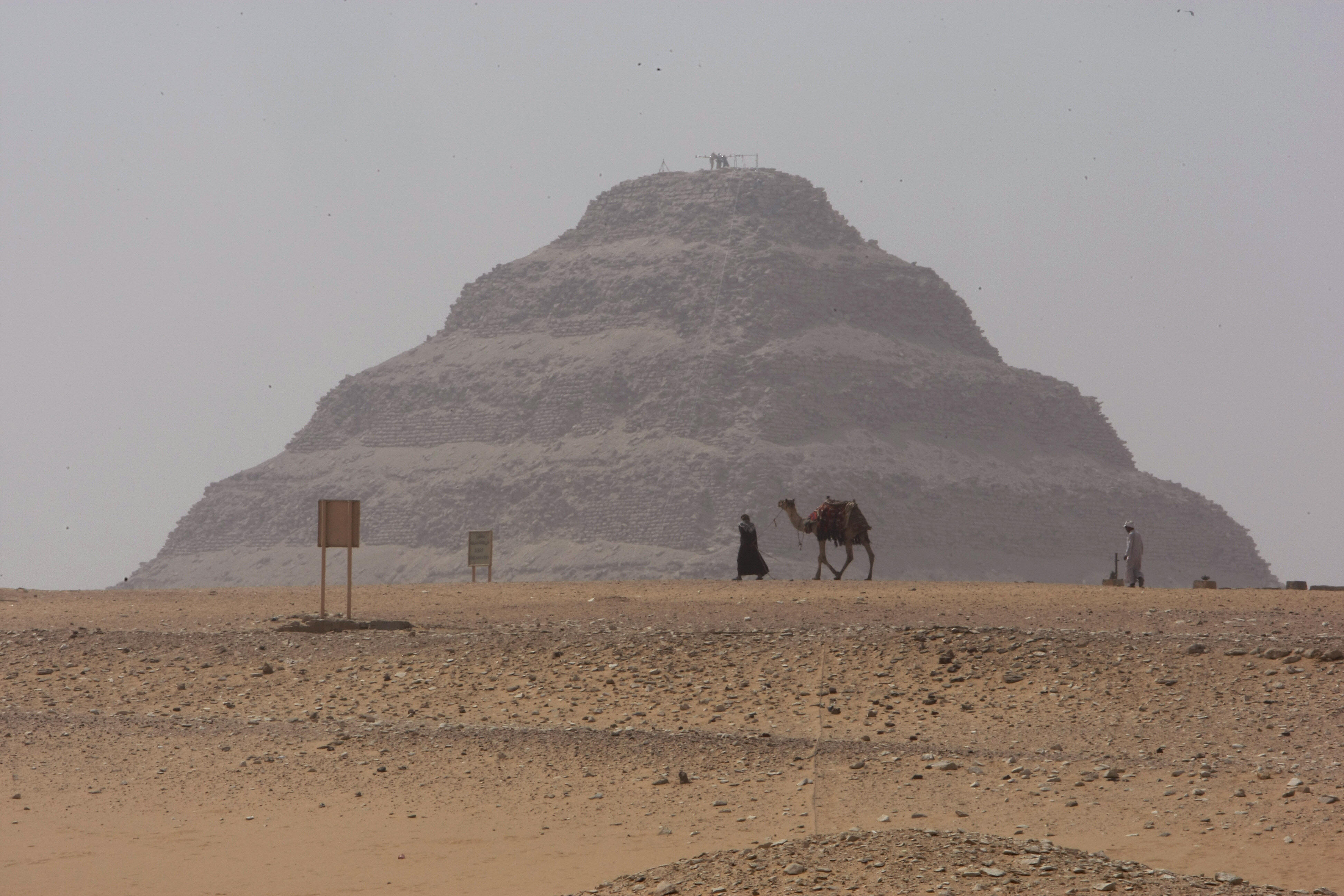 A man walks with his camel on a foggy day past the Step Pyramid of Sakkara, located in the same region as the "Headless Pyramid. A man walks with his camel on a foggy day past the Step Pyramid of Sakkara, located in the same region as the "Headless Pyramid.