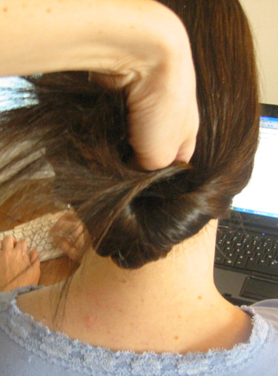 Lift ponytail up and over ponytail holder, right into the hole you created. Push all the way through. Lift ponytail up and over ponytail holder, right into the hole you created. Push all the way through.